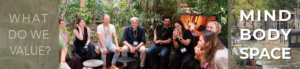 Mind-Body-Space Symposium logo and group photo with multiple participants sitting in a semi-circle in a hotel courtyard, asking "What do we value?"